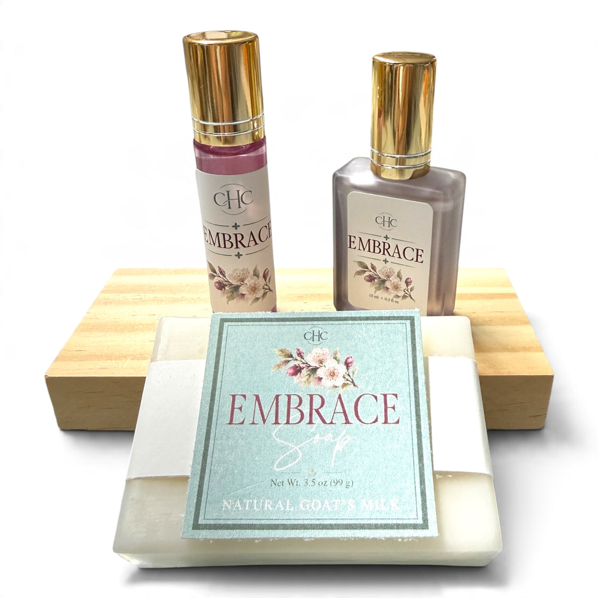 Embrace Scent Trio Gift Set in Cashmere Plum: alcohol-free perfume spray, roll-on perfume and goat milk soap on a wooden soap dish