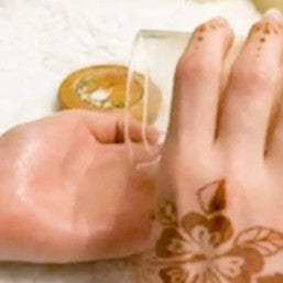 Hand with henna design applying massage candle oil form comfy cozy home to another hand